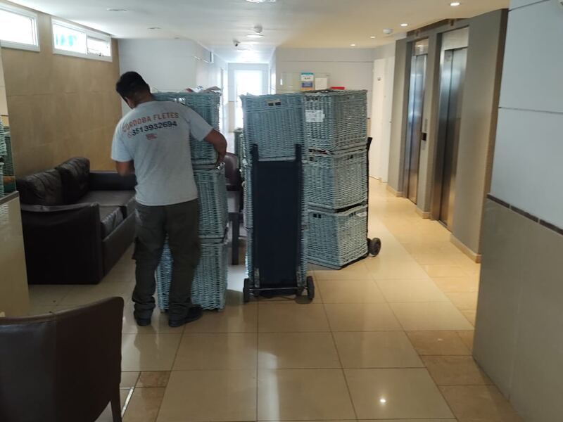 Operario de Córdoba Fletes moviendo canastos de mudanza dentro de un edificio