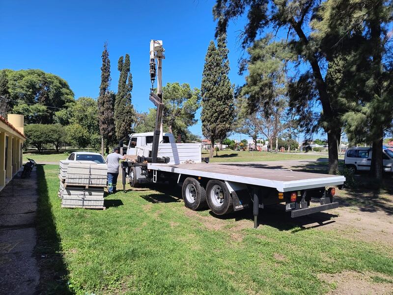 Camión balancín con hidrogrúa descargando placas en destino