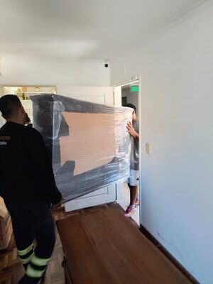 Operario de Córdoba Fletes sacando un mueble embalado por la puerta de un departamento